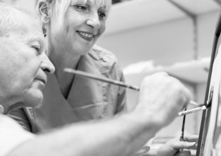 caregiver watching senior doing painting