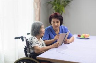 caregiver guiding senior on her reading