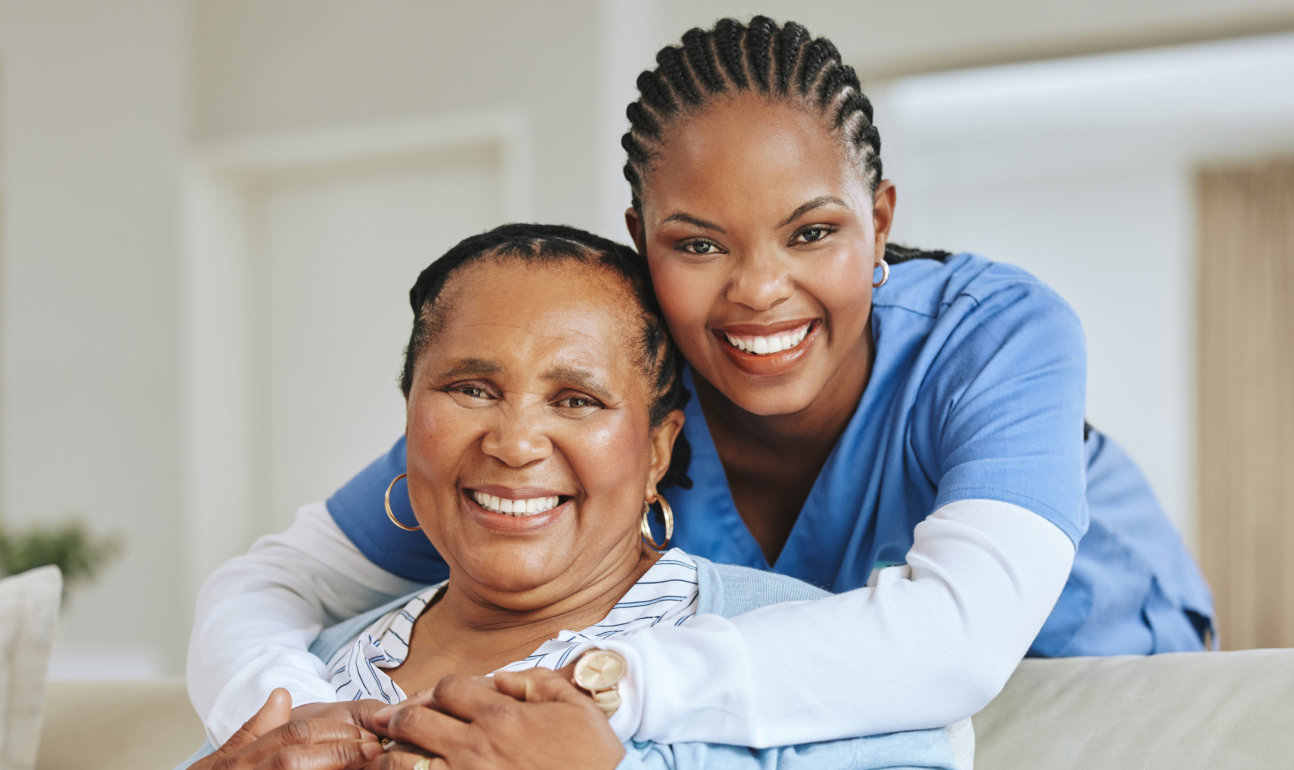 caregiver hugging senior while smiling