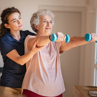 caregiver assisting senior on her exercise